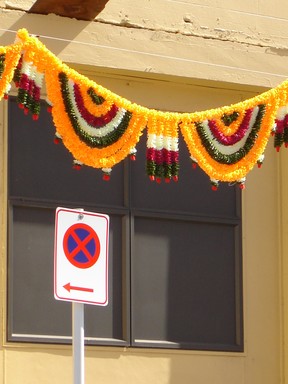 Janet F S Cotton;No stopping;Diwalis hanging decorations in the afternoon sun ablaze of colour against grey building